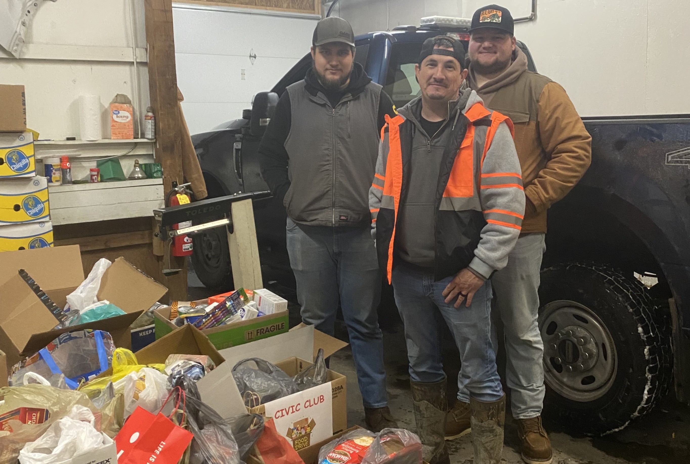 Garrett, Shawn, and Jacob from Brookville public works pose for a photo with food donations collected from Brookville schools.